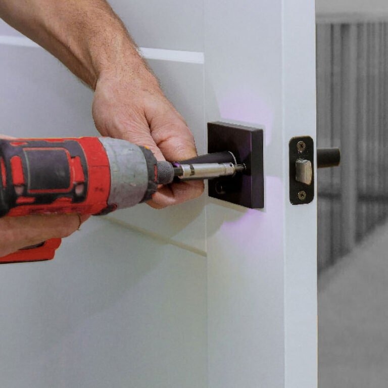 Un serrurier utilise une visseuse pour remplacer une serrure de porte métallique